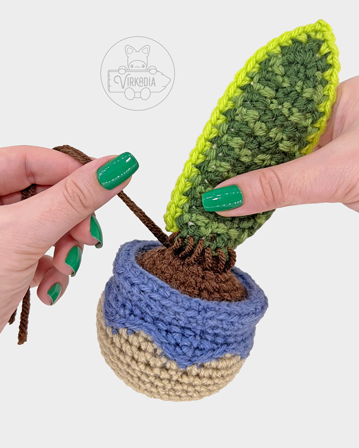 crochet snake plant amigurumi pattern tutorial of how to sew the large leaf onto the pot dirt