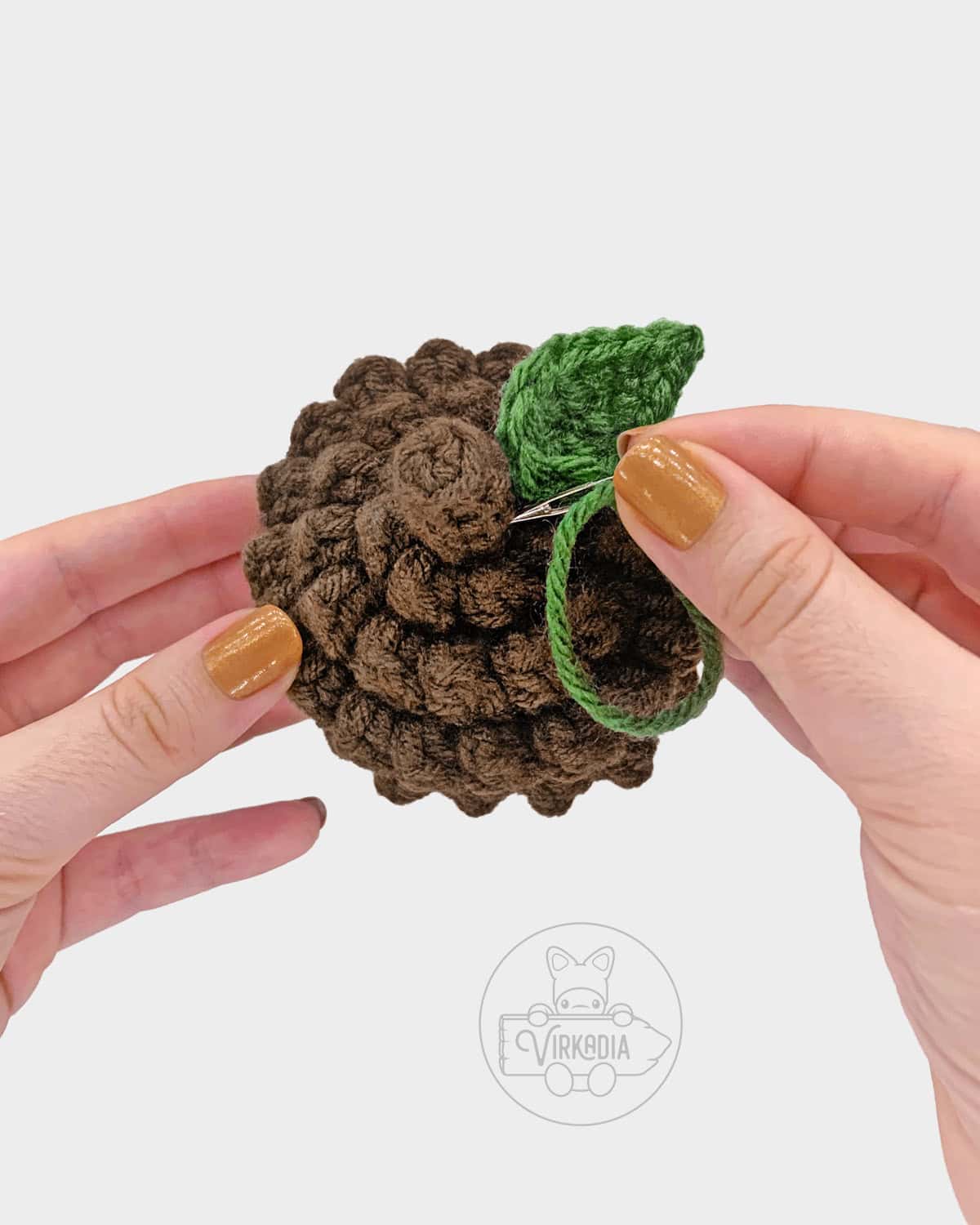 free crochet acorn amigurumi pattern tutorial of how to sew the leaf onto the cap