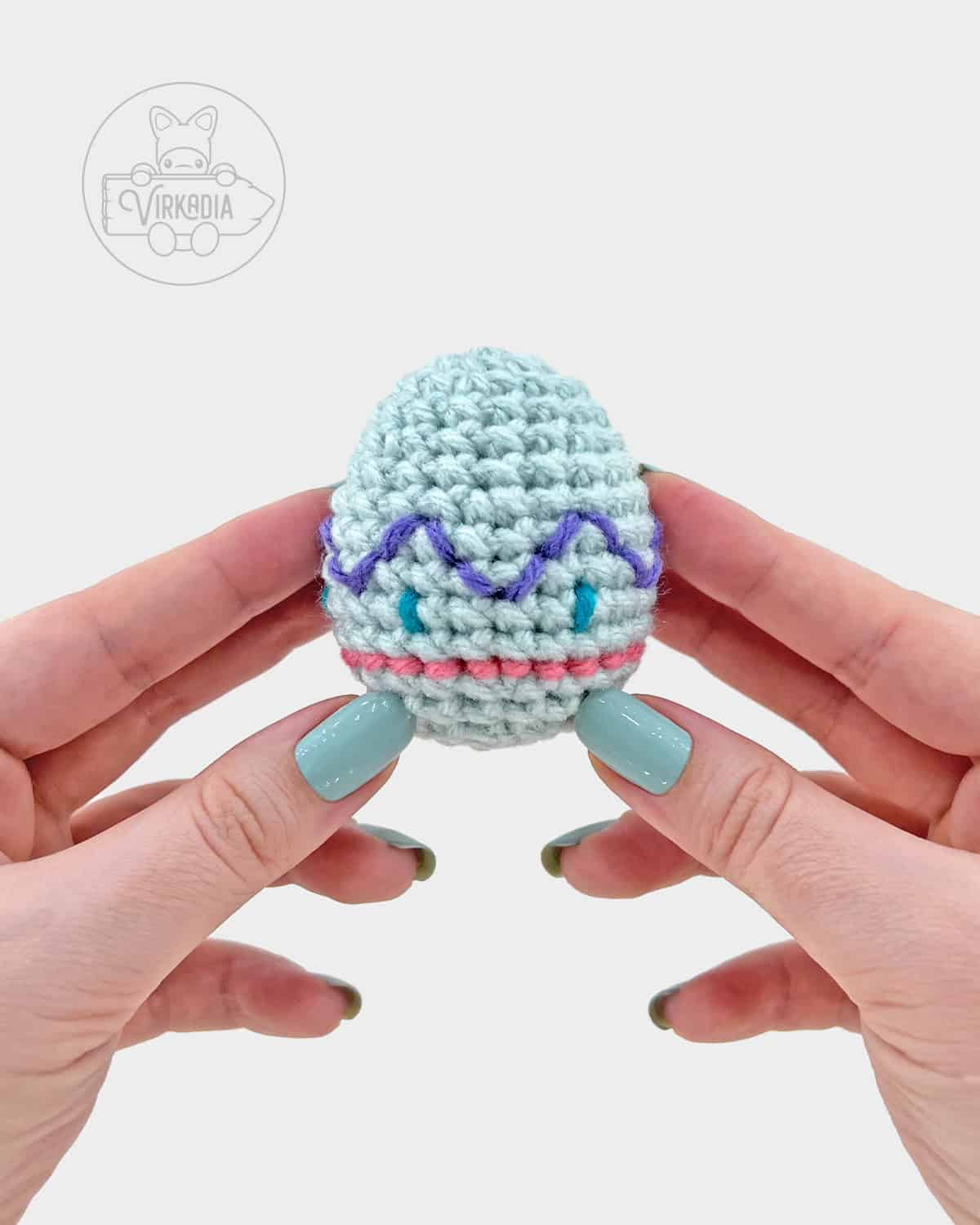 blue-green crochet easter egg amigurumi pattern, completed with embroidered spots, stripe, and zig-zag