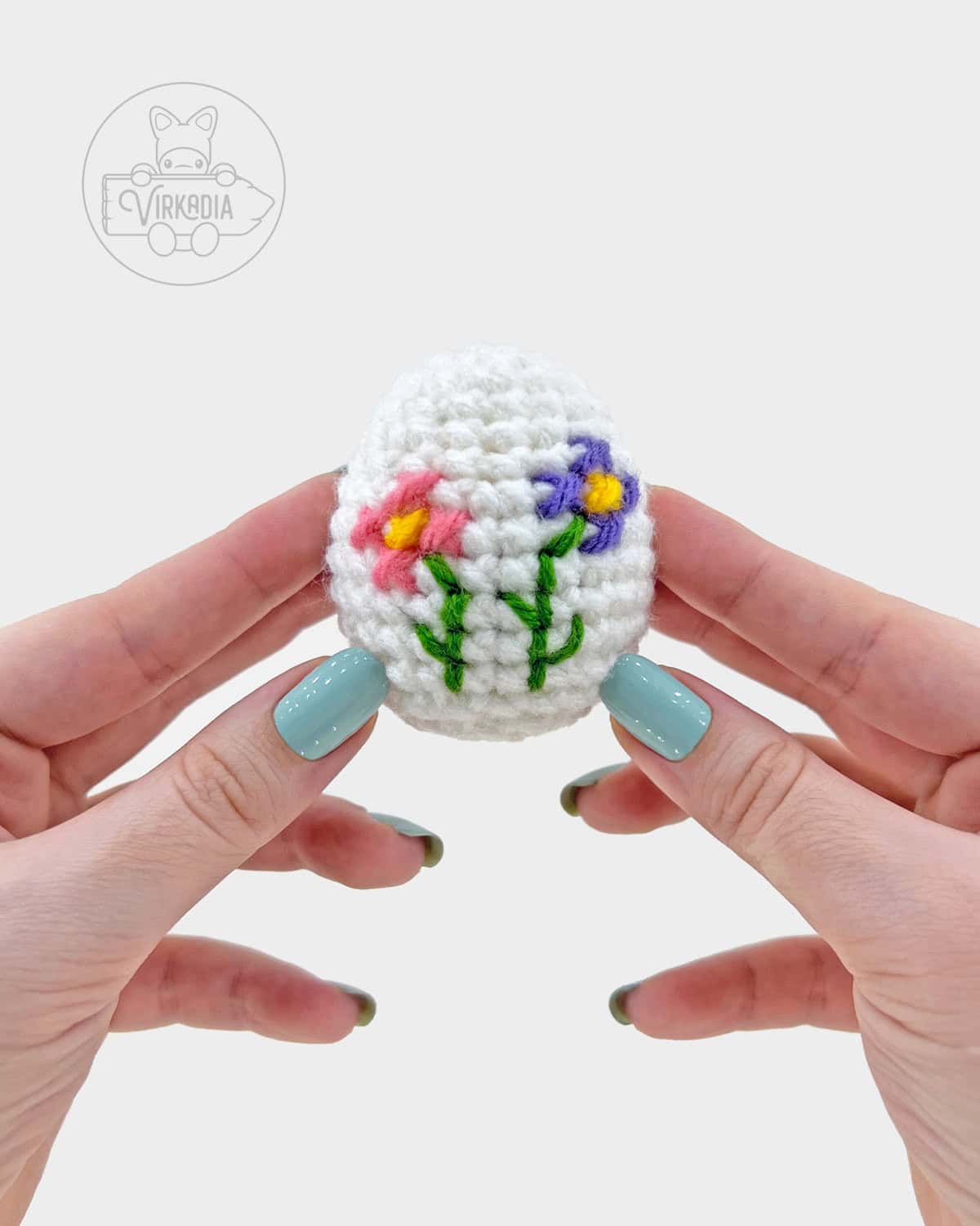 white crochet easter egg amigurumi pattern, completed with cross stitch flowers
