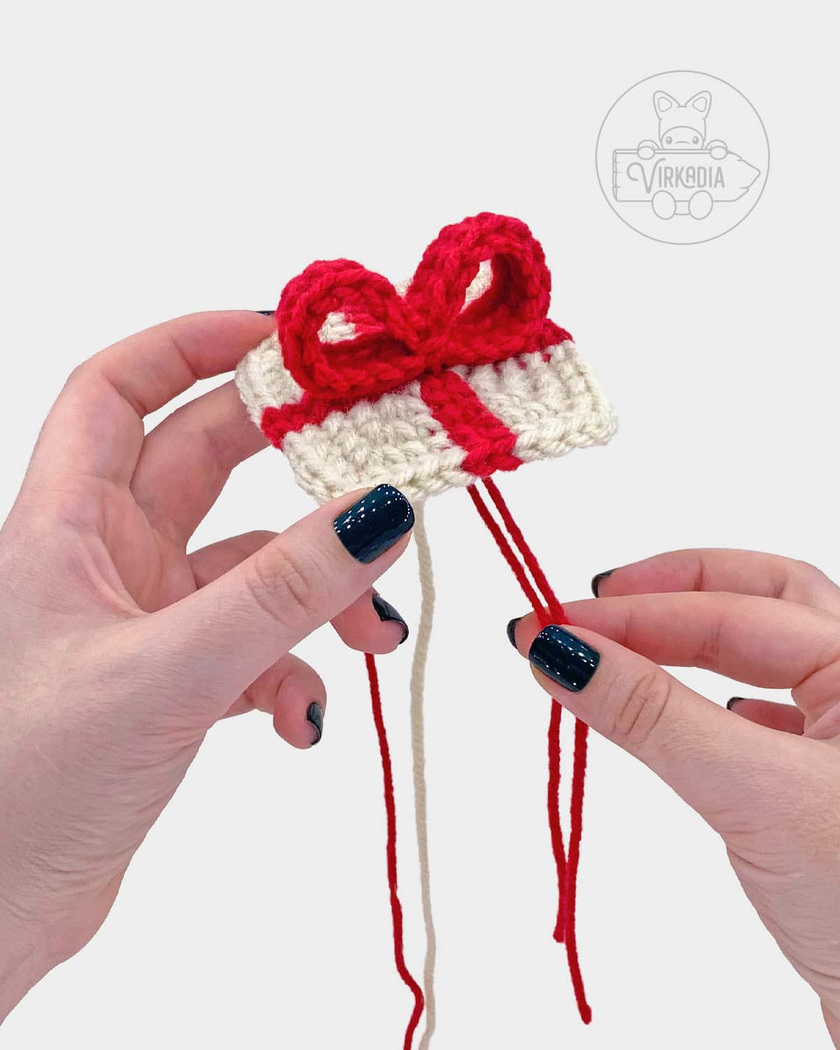 free crochet gift box amigurumi pattern tutorial of how to add the bow to the top of the present