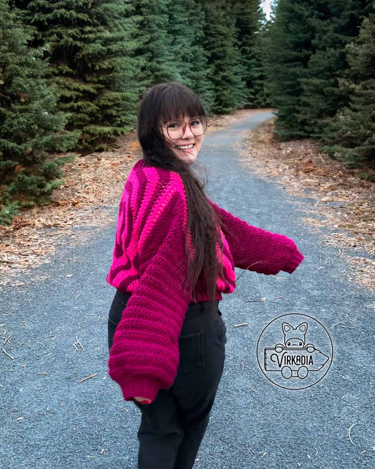 Designer of Virkadia, Joey, posing outside while wearing a crochet heart sweater