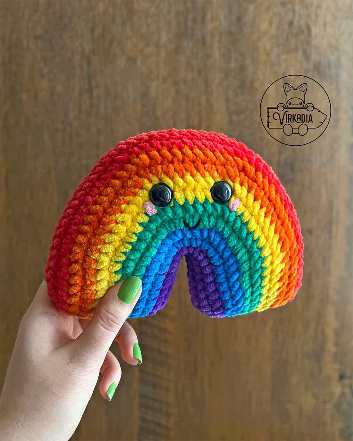 candid shot of crochet rainbow amigurumi plushie in chunky yarn for St. Patrick's Day decorations, spring crafts, DIY Pride Month decor, and handmade gifts