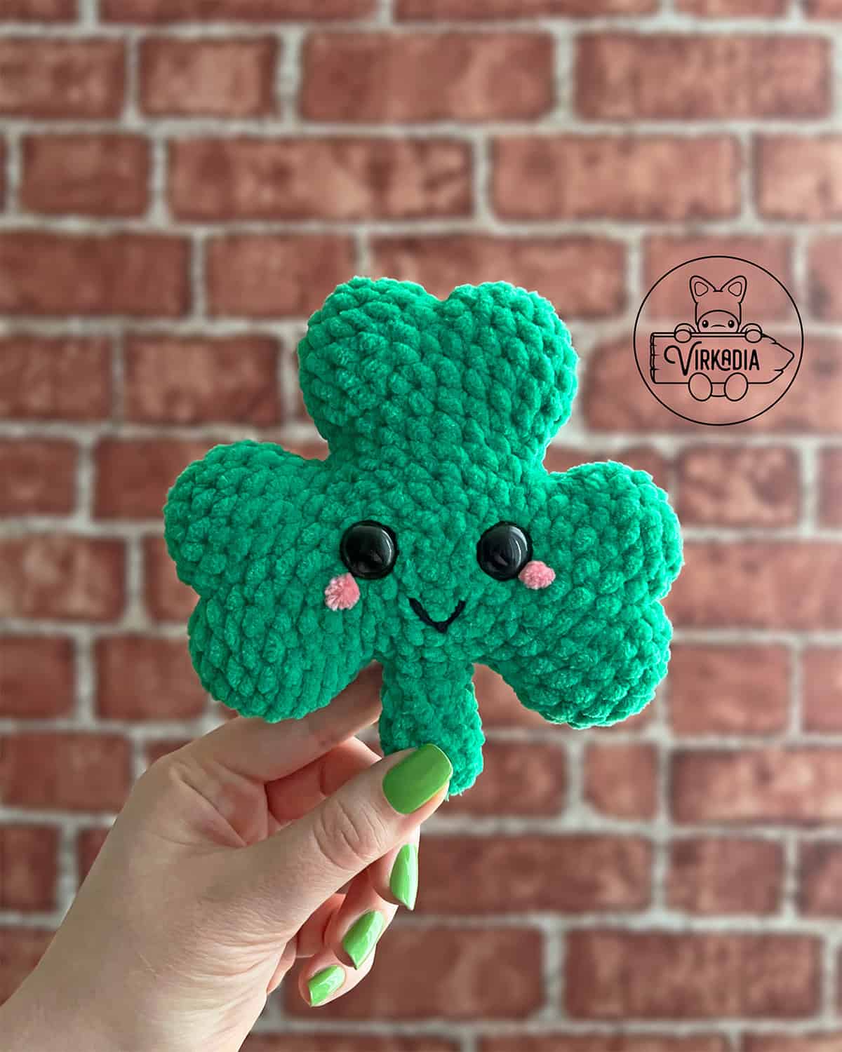 candid shot of crochet shamrock amigurumi plushie in chunky yarn for St. Patrick's Day decorations, spring crafts, DIY holiday decor, and handmade gifts